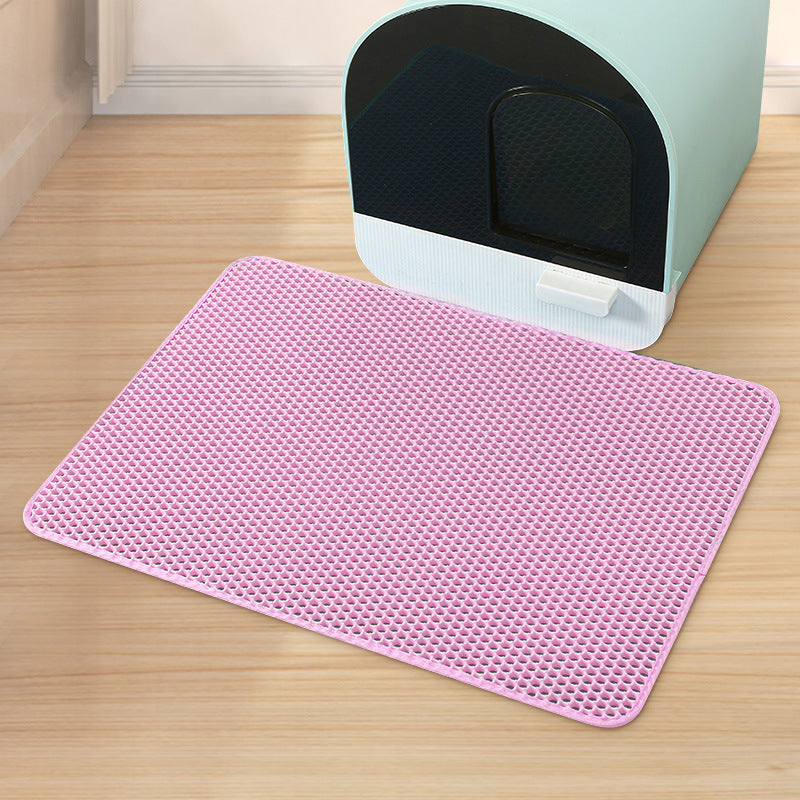 Pink mat on a wooden floor in front of a cat litter box